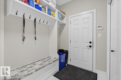 Built-in storage bench with a marbled top, white paneled door, and overhead shelving with integrated hooks - 6813 Knox Loop Sw, Edmonton, AB - Indoor Photo Showing Other Room