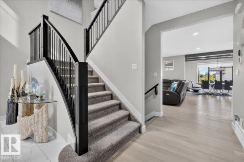 Carpeted staircase with black wrought iron spindles, wood-finish flooring, and white wall finishes - 6813 Knox Loop Sw, Edmonton, AB - Indoor Photo Showing Other Room