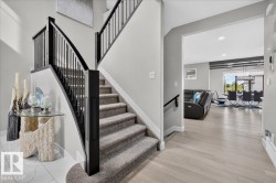 Carpeted staircase with black wrought iron spindles, wood-finish flooring, and white wall finishes - 