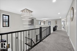Modern chandelier, black wrought iron railing, light gray wall paint, recessed lighting, gray carpeting - 