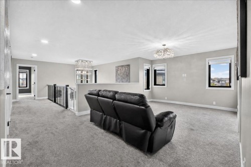 Expansive upper-level space featuring gray carpeting, multiple windows, and a contemporary chandelier - 6813 Knox Loop Sw, Edmonton, AB - Indoor