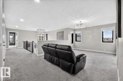 Expansive upper-level space featuring gray carpeting, multiple windows, and a contemporary chandelier - 