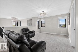 Carpeted open-concept bonus room featuring two distinct crystal chandeliers and multiple windows - 