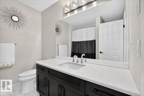Floating vanity with dark wood-finish cabinetry, white stone countertop, undermount sink, and polished chrome faucet - 6813 Knox Loop Sw, Edmonton, AB - Indoor Photo Showing Bathroom