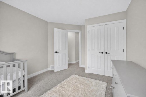 Light gray wall tones with white trim, gray carpeting, and white paneled doors with black hardware - 6813 Knox Loop Sw, Edmonton, AB - Indoor Photo Showing Bedroom