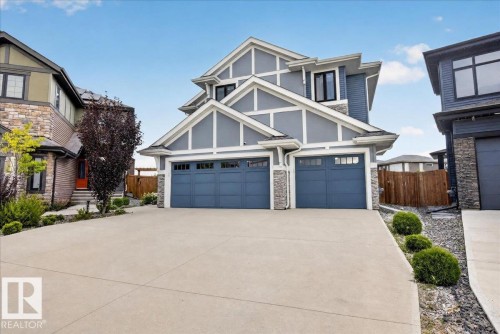 Modern exterior with multiple gables, gray siding, stone accents, two garage doors, and a concrete driveway - 6813 Knox Loop Sw, Edmonton, AB - Outdoor With Facade