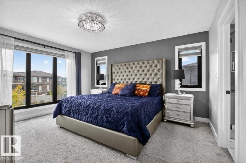 Wall-to-wall carpeting, large picture windows, and a modern flush-mount chandelier - 6813 Knox Loop Sw, Edmonton, AB - Indoor Photo Showing Bedroom