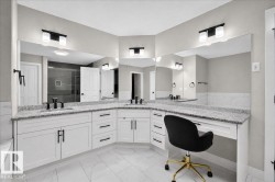 Corner vanity with dual sinks, granite countertops, white cabinetry, and matte black fixtures - 