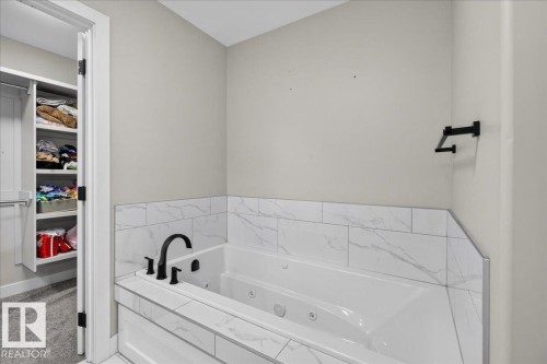 Jetted soaking tub with matte black fixtures and a tiled surround - 6813 Knox Loop Sw, Edmonton, AB - Indoor Photo Showing Bathroom