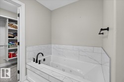 Jetted soaking tub with matte black fixtures and a tiled surround - 