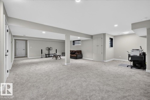 Expansive carpeted area with recessed lighting, two windows with horizontal blinds, and a built-in storage cabinet - 6813 Knox Loop Sw, Edmonton, AB - Indoor