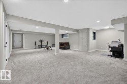 Expansive carpeted area with recessed lighting, two windows with horizontal blinds, and a built-in storage cabinet - 