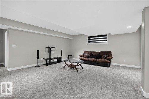Spacious room featuring gray carpet, light gray walls, white trim, and a window with horizontal blinds - 6813 Knox Loop Sw, Edmonton, AB - Indoor