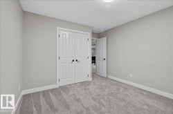 Neutral wall tones with white trim, gray patterned carpeting, and white bifold doors - 