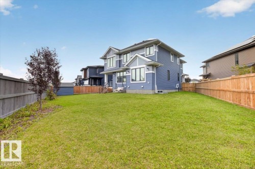 Expansive rear yard with a manicured lawn, full privacy fencing, and exterior lighting fixtures - 6813 Knox Loop Sw, Edmonton, AB - Outdoor