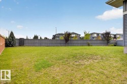 Expansive lawn with mature landscaping and established perimeter fencing, offering substantial outdoor space - 