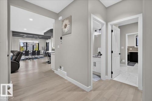 Wide plank wood-finish flooring, light grey painted walls, white trim, recessed ceiling lighting, and a white interior door - 6813 Knox Loop Sw, Edmonton, AB - Indoor Photo Showing Other Room
