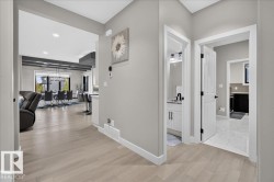 Wide plank wood-finish flooring, light grey painted walls, white trim, recessed ceiling lighting, and a white interior door - 