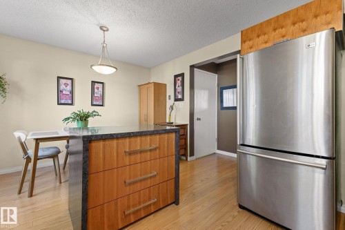 Kitchen island with dark countertop and wood-finish cabinetry - 17132 103 Street Nw, Edmonton, AB 