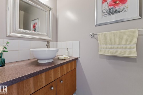 Wood-finish vanity with a dark countertop and vessel sink - 17132 103 Street Nw, Edmonton, AB 