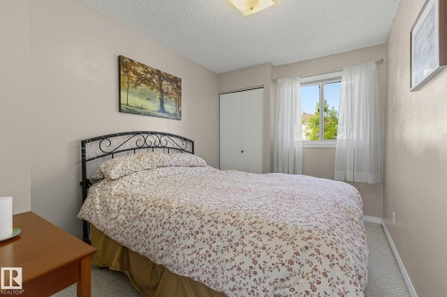 Neutral wall paint, ceiling-mounted light fixture, white window trim, white bi-fold closet doors, and light-toned carpet flooring - 17132 103 Street Nw, Edmonton, AB 