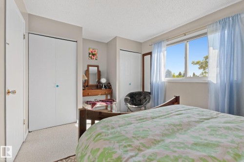 Spacious room featuring neutral carpeting, a large window, and multiple built-in closets - 17132 103 Street Nw, Edmonton, AB 