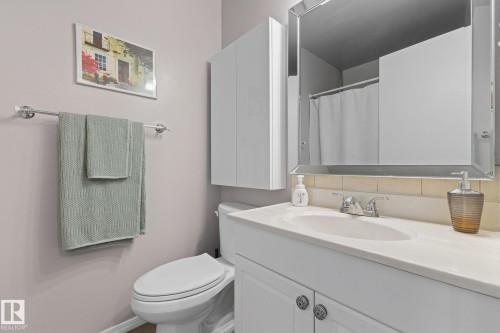 Bathroom featuring a white vanity with an integrated sink, polished chrome faucet, and a wall-mounted mirror - 17132 103 Street Nw, Edmonton, AB 