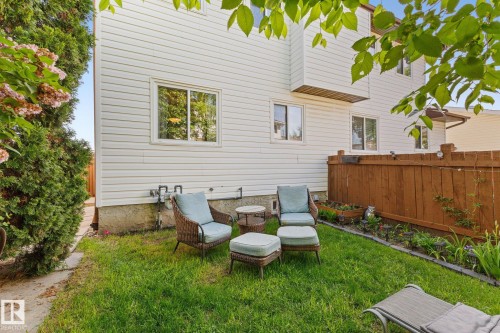Manicured lawn area with a privacy fence, multiple windows, and a raised garden bed - 17132 103 Street Nw, Edmonton, AB 
