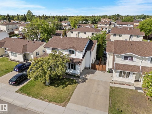 White two-story residence with a brown shingled roof, featuring a concrete driveway and an attached single-car garage - 17132 103 Street Nw, Edmonton, AB 