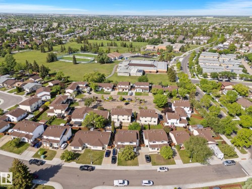 Expansive residential neighborhood featuring single-family homes with brown shingle roofs, mature trees, and a substantial green space with athletic fields - 17132 103 Street Nw, Edmonton, AB 