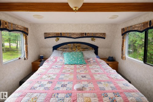 Built-in wood-finish headboard with integrated sconce lighting, two windows with valances, and wood-finish ceiling trim - 506 60017 Range Road 110 A, Rural St. Paul County, AB 