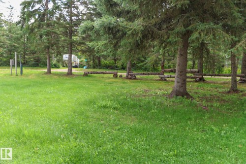 Manicured lawn with mature evergreen trees and a rustic wood fence - 506 60017 Range Road 110 A, Rural St. Paul County, AB 