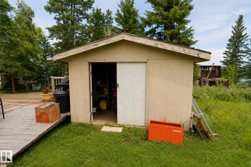 Detached shed with an open sliding door, wood-finish decking, and surrounding grass - 506 60017 Range Road 110 A, Rural St. Paul County, AB 