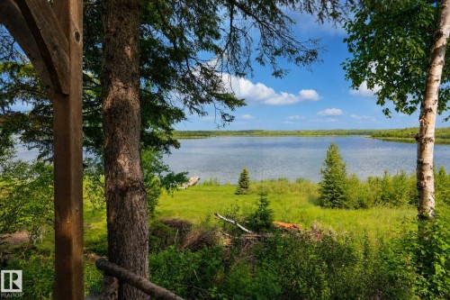 Expansive waterfront property featuring a large body of water, mature trees, and a clear blue sky - 506 60017 Range Road 110 A, Rural St. Paul County, AB 