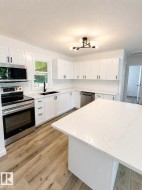 Modern kitchen featuring white shaker cabinetry, stainless steel appliances, a white subway tile backsplash, and wood-finish flooring - 