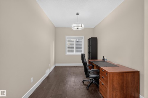Dark wood-finish flooring, neutral wall tones, and a single window with blinds - 7014 Chivers Loop Sw, Edmonton, AB 