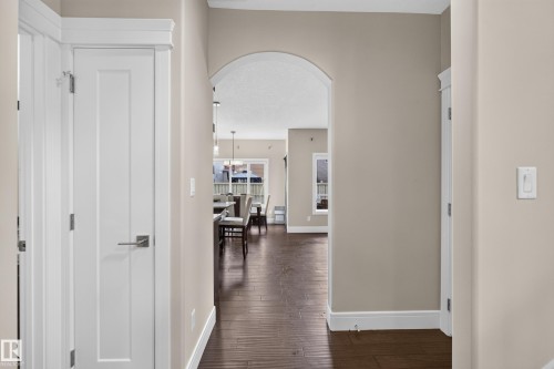 Archway entry, wood-finish flooring, white paneled doors, neutral wall paint, and white trim - 7014 Chivers Loop Sw, Edmonton, AB 