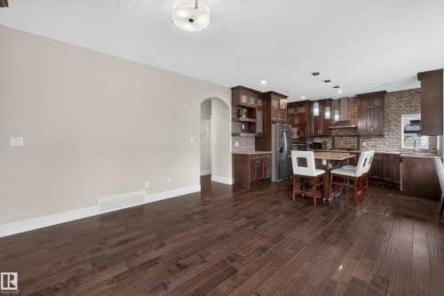 Dark wood-finish flooring, recessed lighting, archway, dark wood cabinetry, and stainless steel appliances - 7014 Chivers Loop Sw, Edmonton, AB 