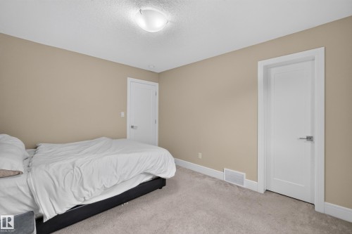 Neutral tone wall color, light-colored carpeting, white trim, modern interior doors with hardware, and a ceiling-mounted light fixture - 7014 Chivers Loop Sw, Edmonton, AB 