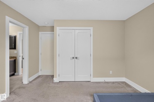 Neutral tone wall paint, white trim, gray carpet flooring, white paneled doors, and recessed lighting - 7014 Chivers Loop Sw, Edmonton, AB 