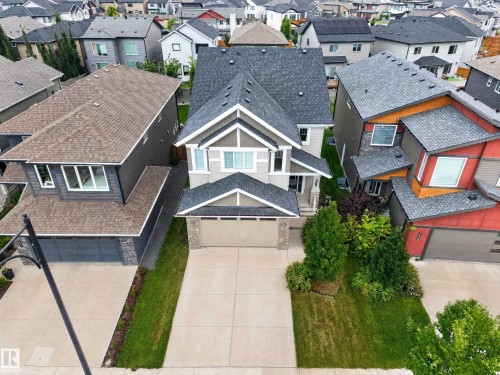 Contemporary two-story residence featuring a two-car garage, concrete driveway, and front lawn landscaping - 7014 Chivers Loop Sw, Edmonton, AB 