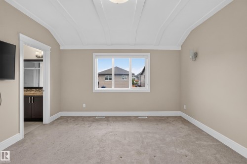 Tray ceiling, neutral paint, light carpeting, white window trim, and wall sconce - 7014 Chivers Loop Sw, Edmonton, AB 
