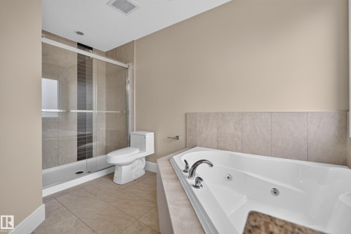 Spacious bathroom featuring a glass-enclosed shower, a built-in jetted tub, and tile flooring - 7014 Chivers Loop Sw, Edmonton, AB 