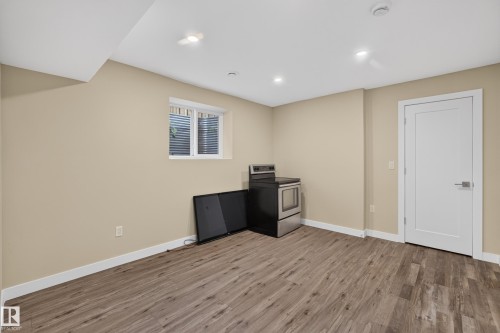 Neutral wall paint, wood-finish flooring, recessed lighting, white trim, and a white door with brushed nickel hardware - 7014 Chivers Loop Sw, Edmonton, AB 