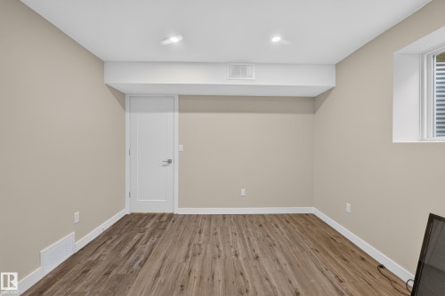 Recessed lighting, light beige wall paint, wood-finish flooring, white trim, and a white interior door - 7014 Chivers Loop Sw, Edmonton, AB 