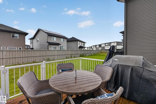 Wood-finish deck with white railing, featuring a spacious grass area beyond a privacy fence - 7014 Chivers Loop Sw, Edmonton, AB 