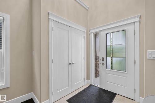 Entryway featuring a white paneled door with decorative glass, a sidelight, and light-toned floor tile - 7014 Chivers Loop Sw, Edmonton, AB 