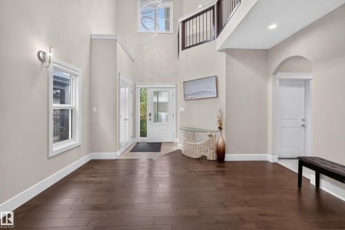 Two-story foyer with a vaulted ceiling, wood-finish flooring, and white trim - 7014 Chivers Loop Sw, Edmonton, AB 