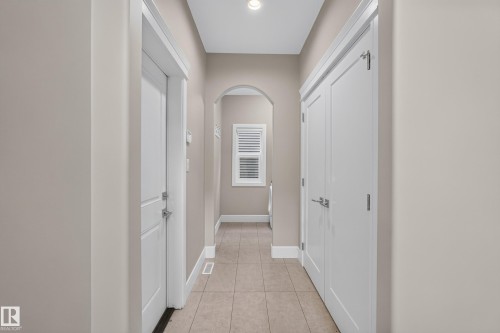Tile flooring, arched entryway, white interior doors, window with louvered shutters, recessed lighting - 7014 Chivers Loop Sw, Edmonton, AB 