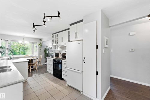 Kitchen featuring white cabinetry, a black range with an overhead microwave, and white appliances - 5208 105 Street Nw, Edmonton, AB - Indoor Photo Showing Kitchen With Double Sink